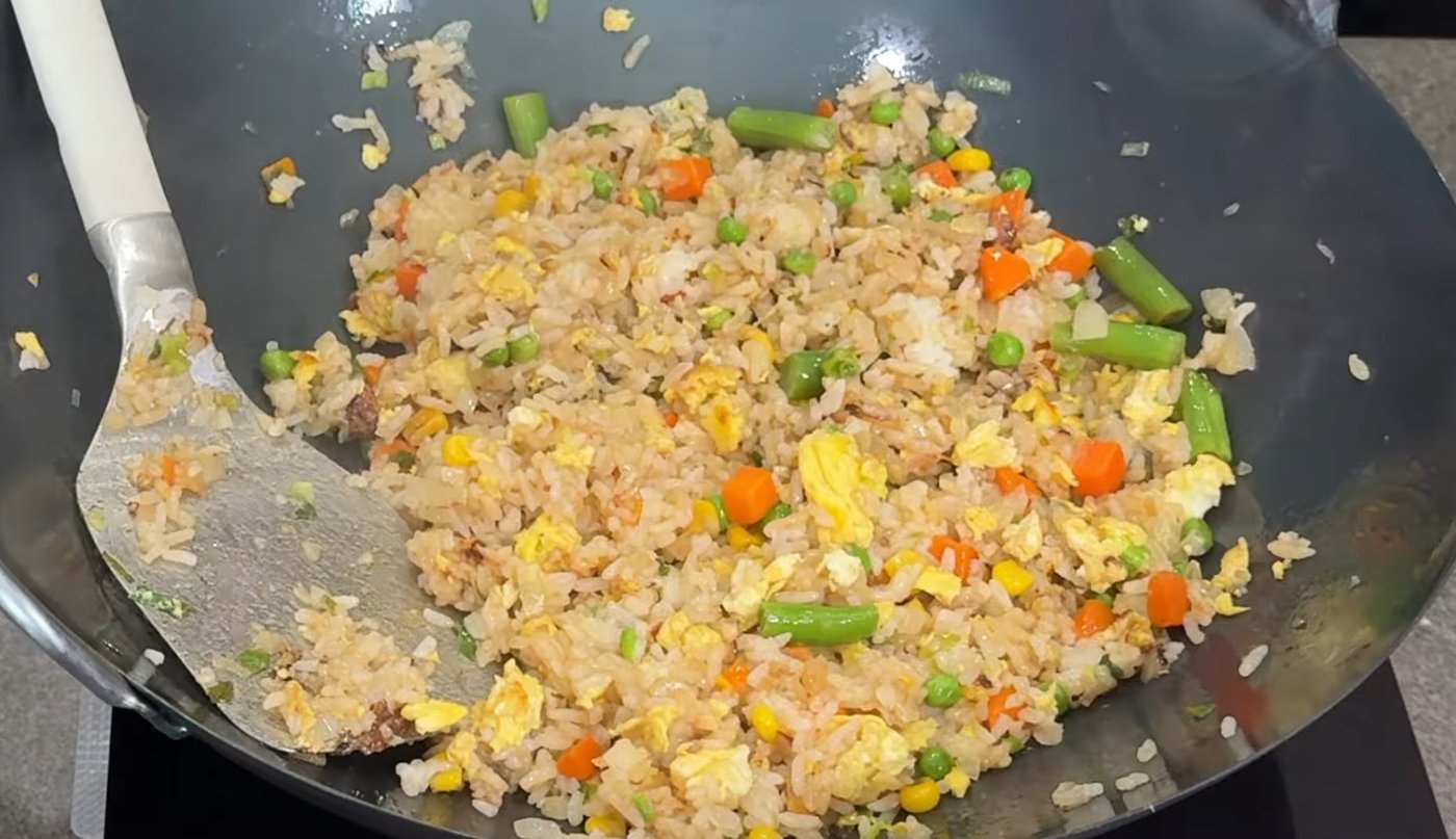 American Chinese fried rice with peas, carrots, corn, and egg in a wok
