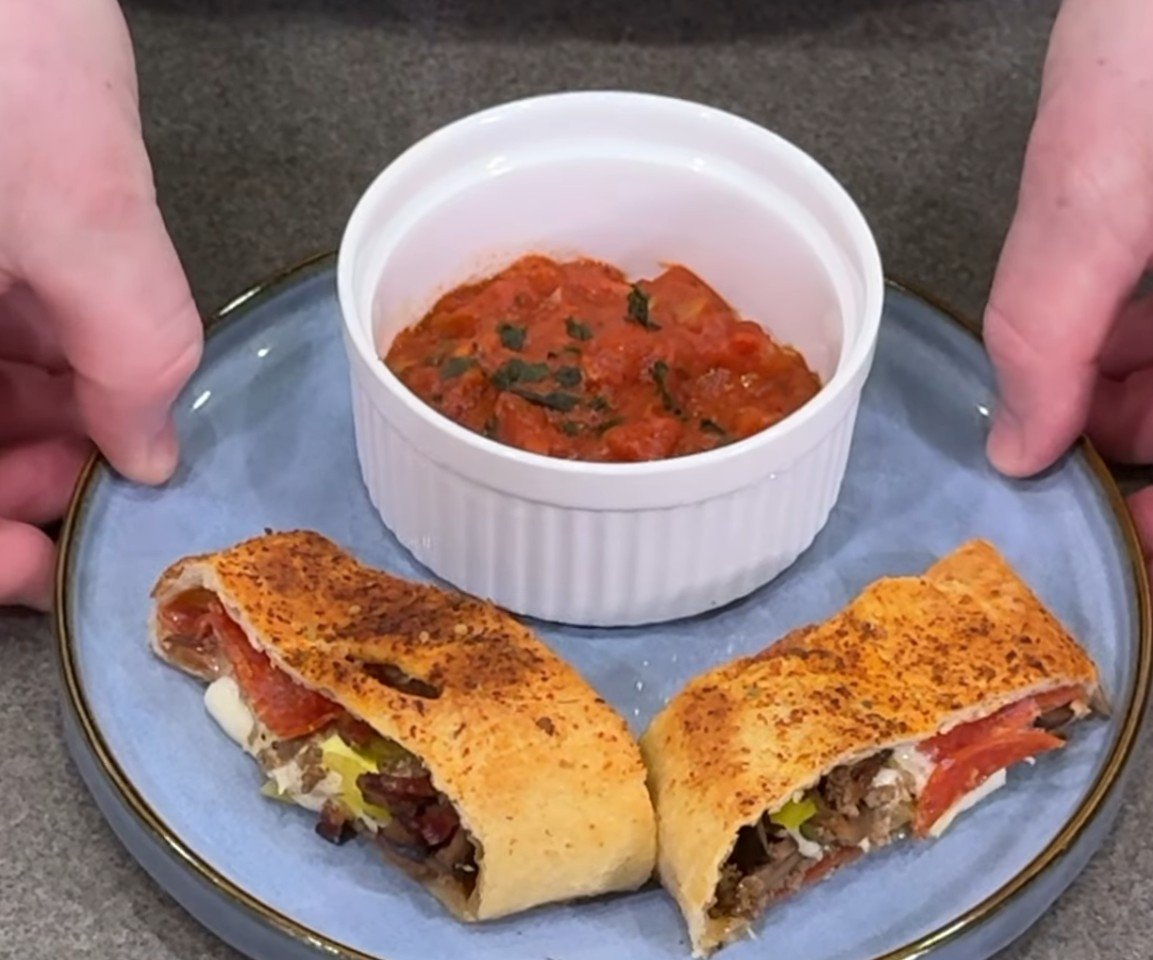 Sliced stromboli with a bowl of homemade marinara for dipping
